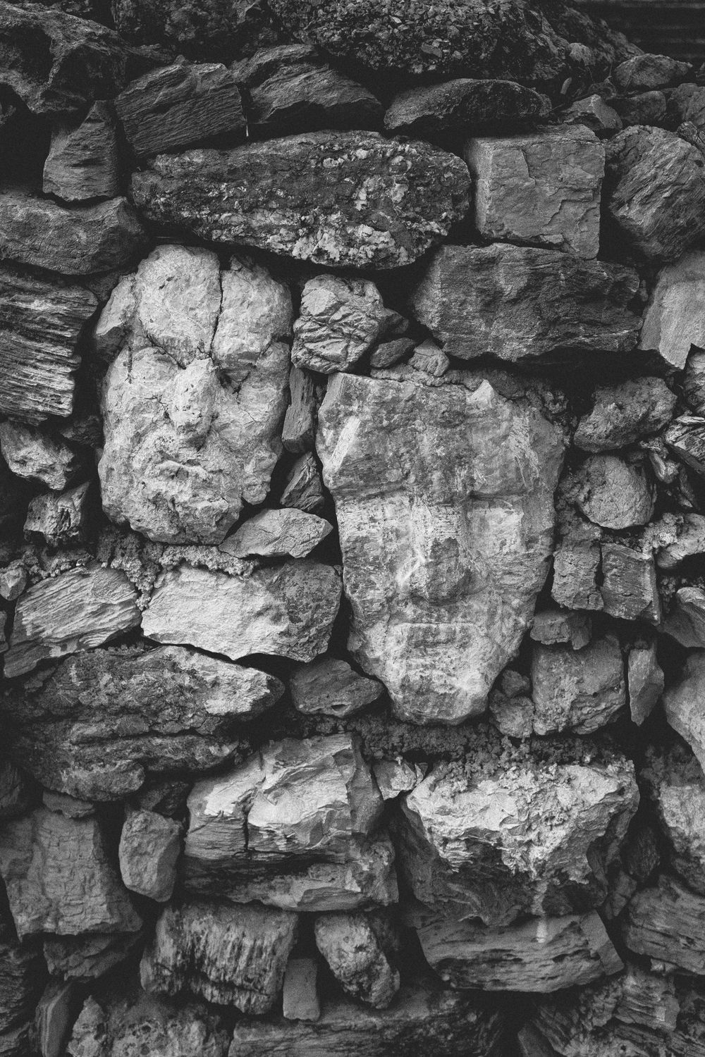 Close-up black and white photo of an old stone wall showing rough textured rocks stacked in a rustic pattern.