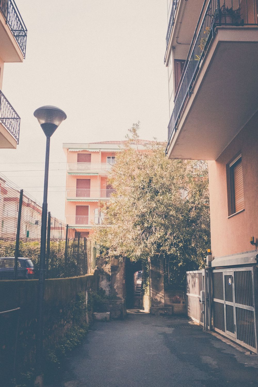 Urban residential street with lamp post and pink apartment buildings in a Mediterranean style setting during sunset.