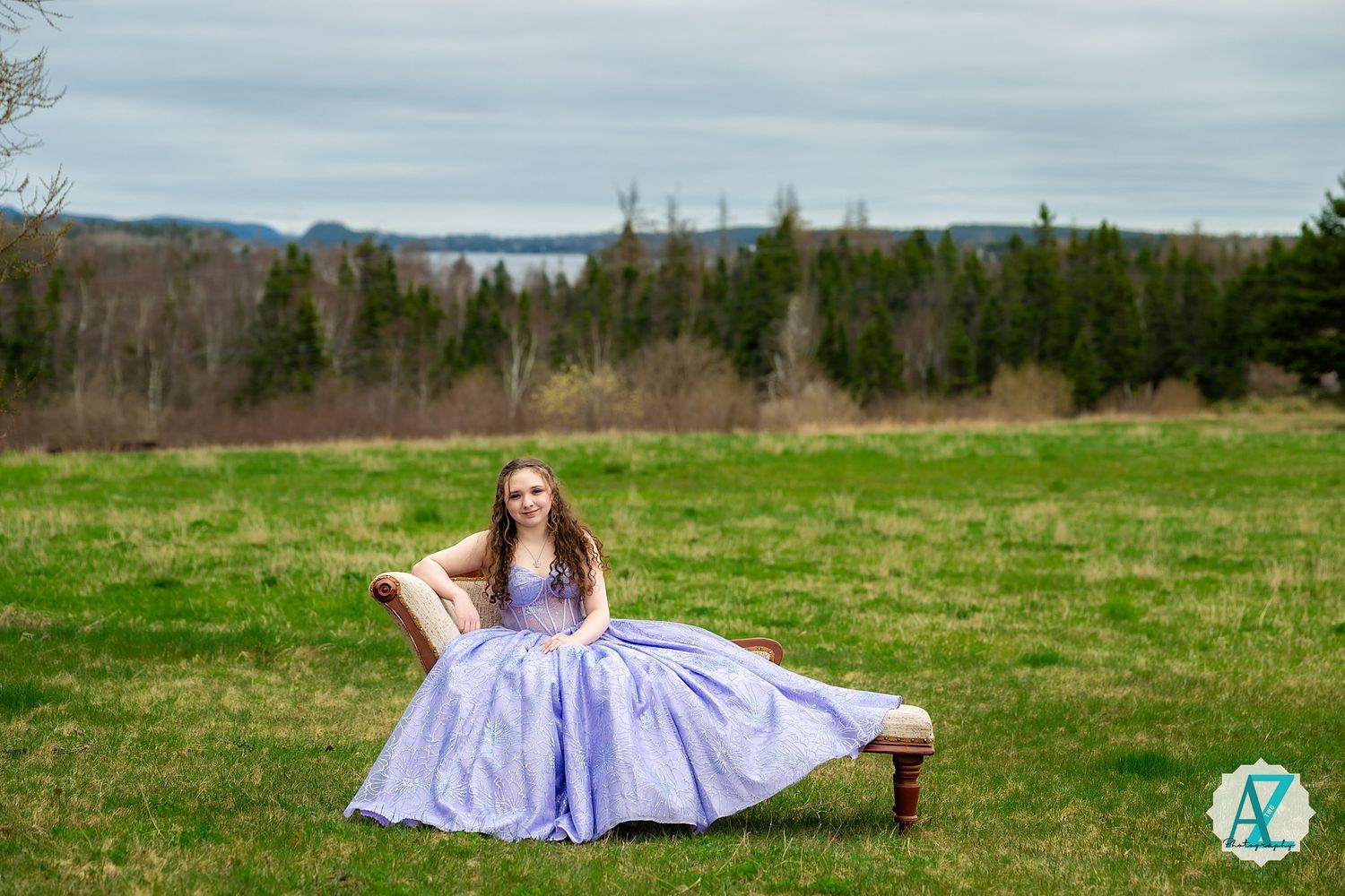 A flowing lavender ballgown creates a regal scene on a rustic bench with forest and mountains in the background.