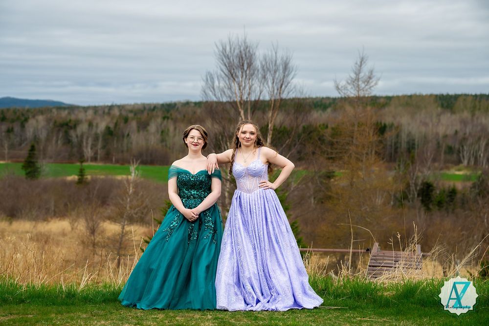 Two elegant gowns in teal and lavender stand out against an autumn countryside landscape.