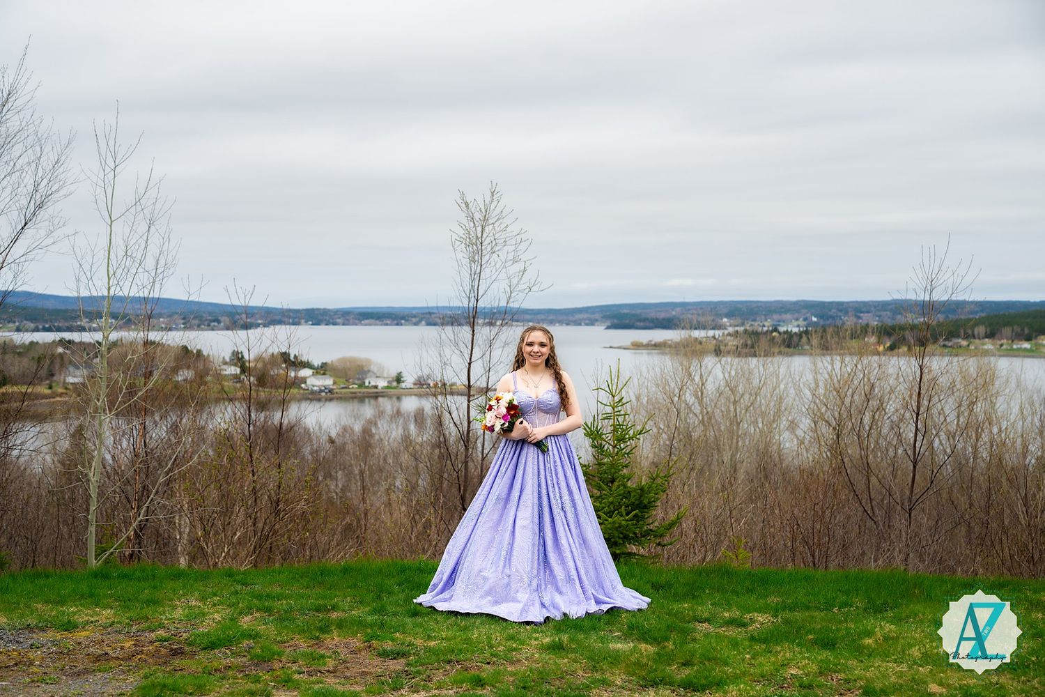 A lavender ballgown creates an enchanting silhouette against a scenic lake and mountain backdrop.