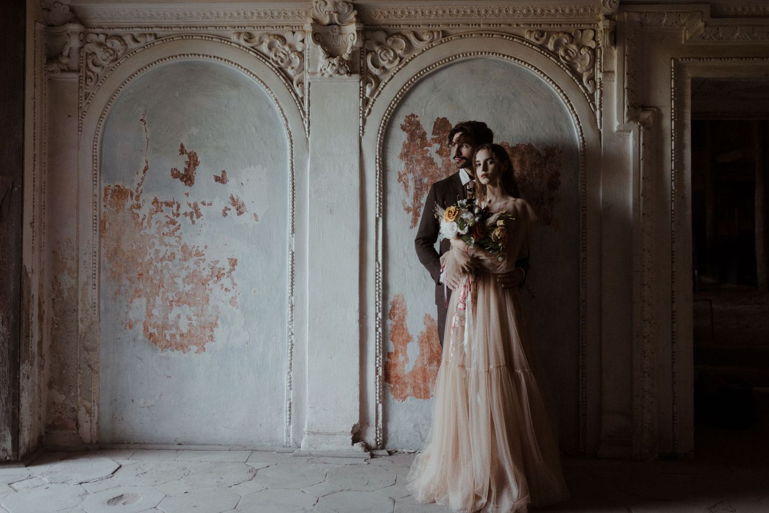 A poetic wedding moment captured in a decaying room with ornate moldings, featuring an ethereal champagne-colored gown.