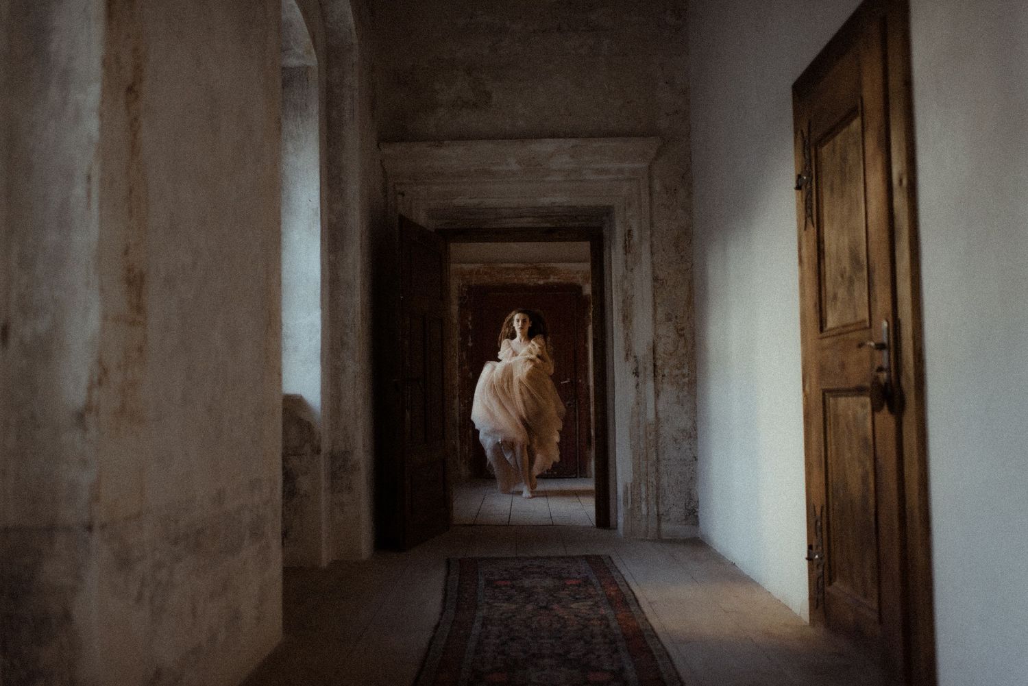 A dreamy corridor scene shows a figure in flowing dress suspended in mid-air between vintage wooden doorways.