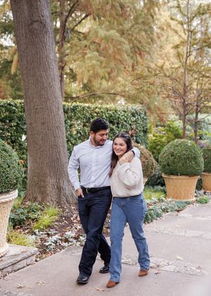 A couple spending time together on a garden path with manicured hedges and autumn foliage in the background.