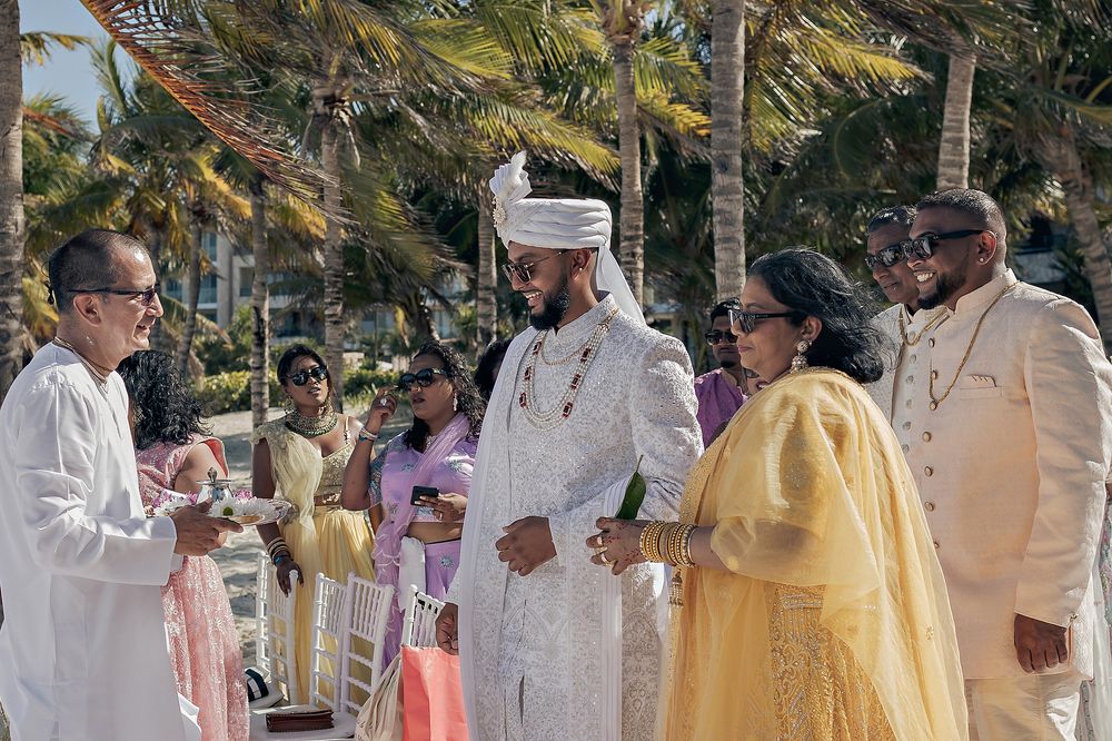 Outdoor ceremony taking place among palm trees with guests dressed in formal attire.