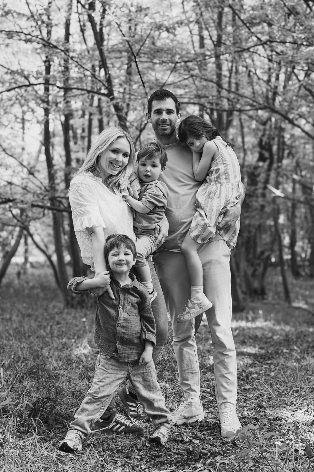 Family of four posing together in a forest setting in black and white.