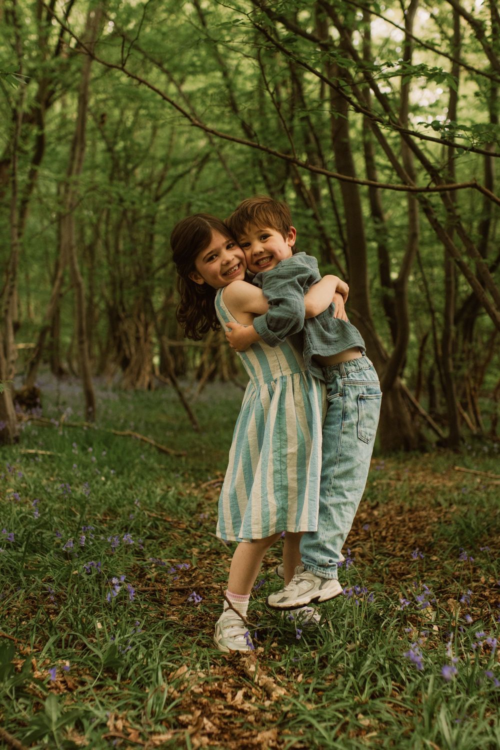 Playful moment between two people in a forest with blooming spring flowers.