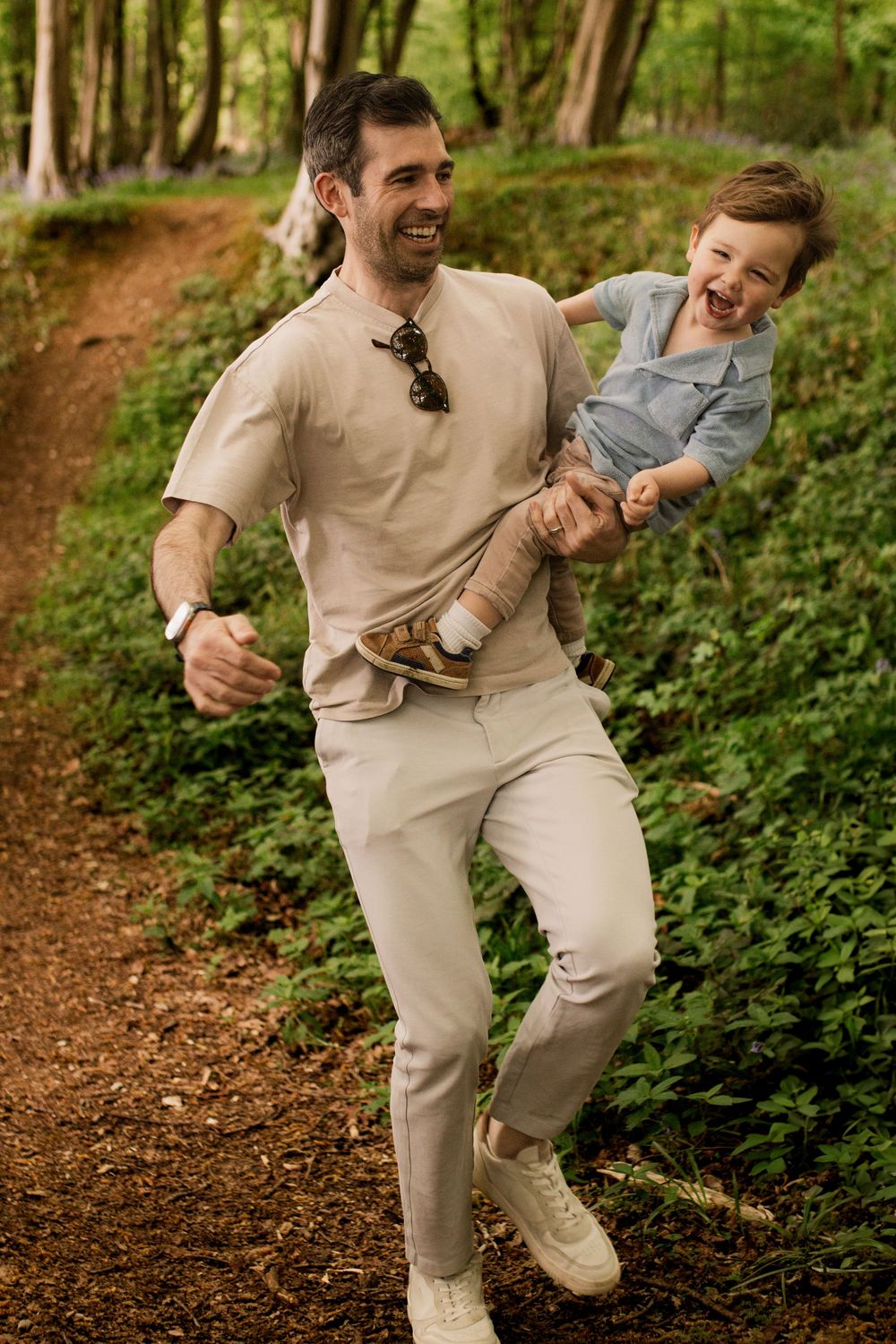 Joyful moment of play on a forest trail with sunlight filtering through trees.