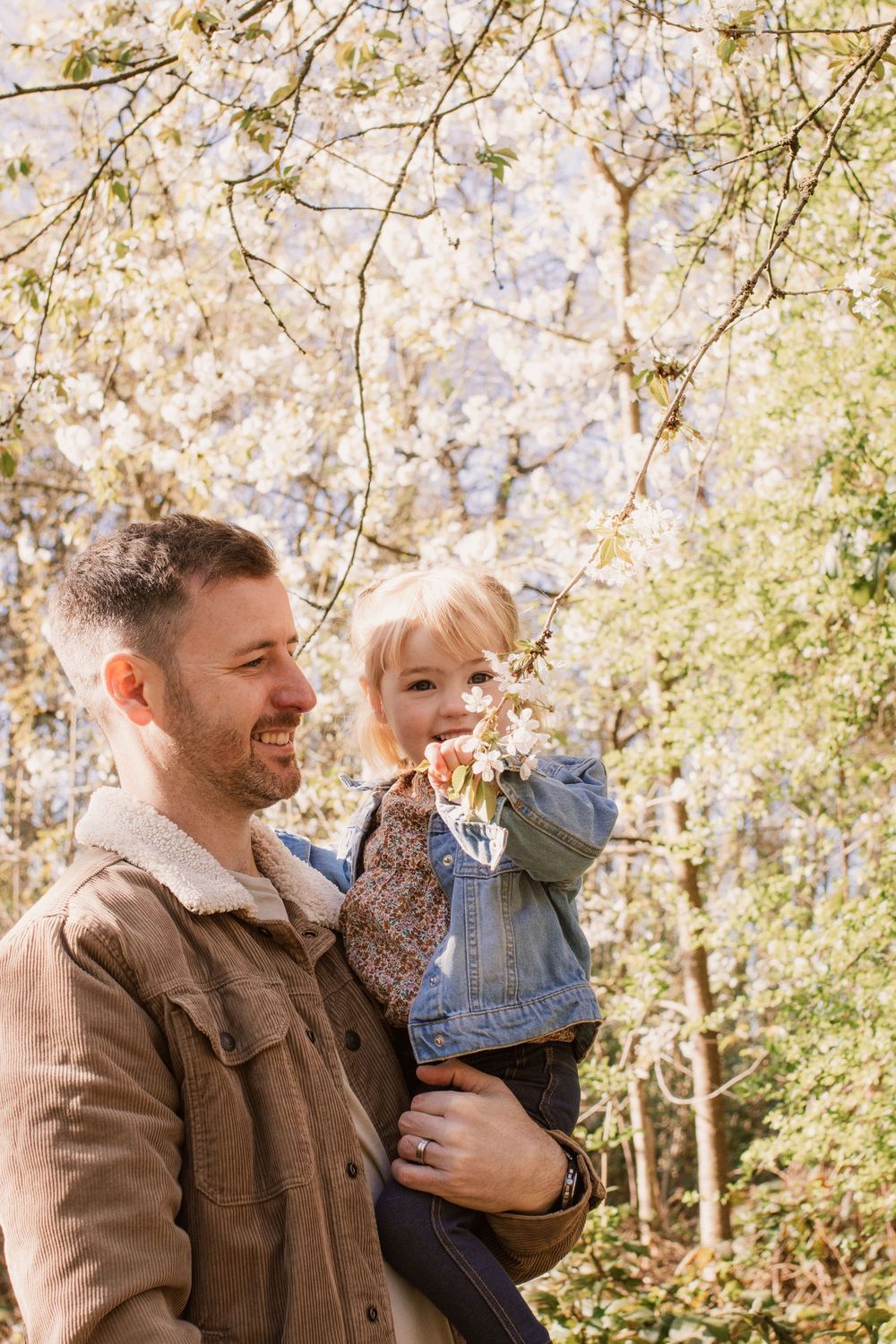 A joyful outdoor moment in nature with brown jackets and spring blossoms.