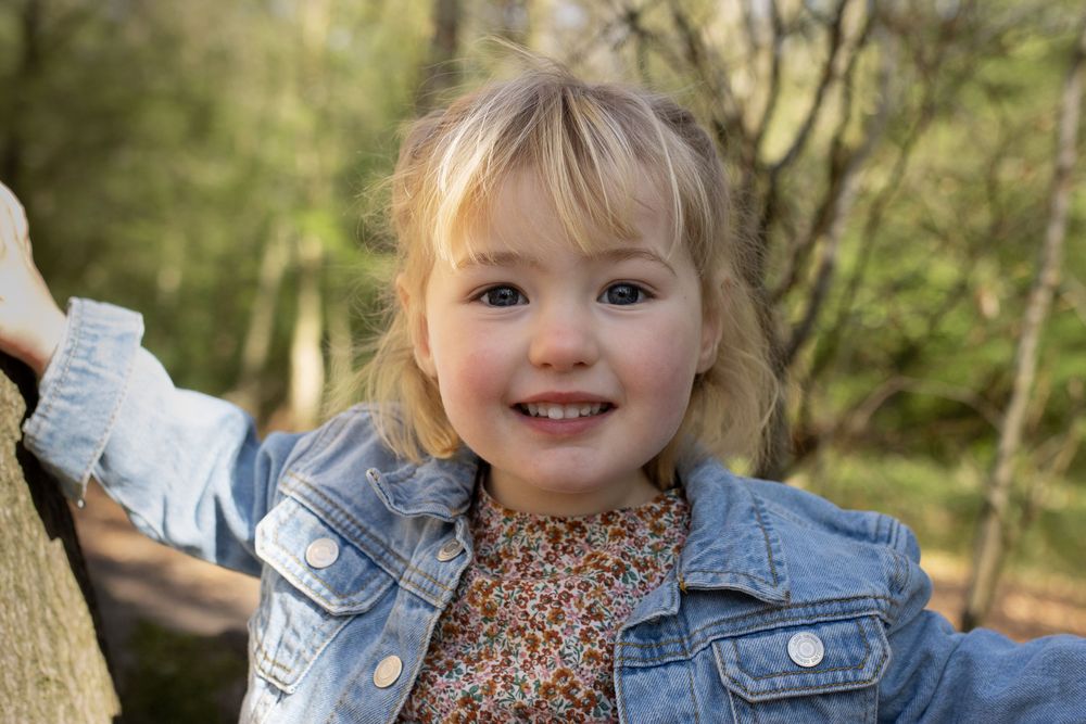 Sweet outdoor portrait in denim and brown jackets against natural backdrop.