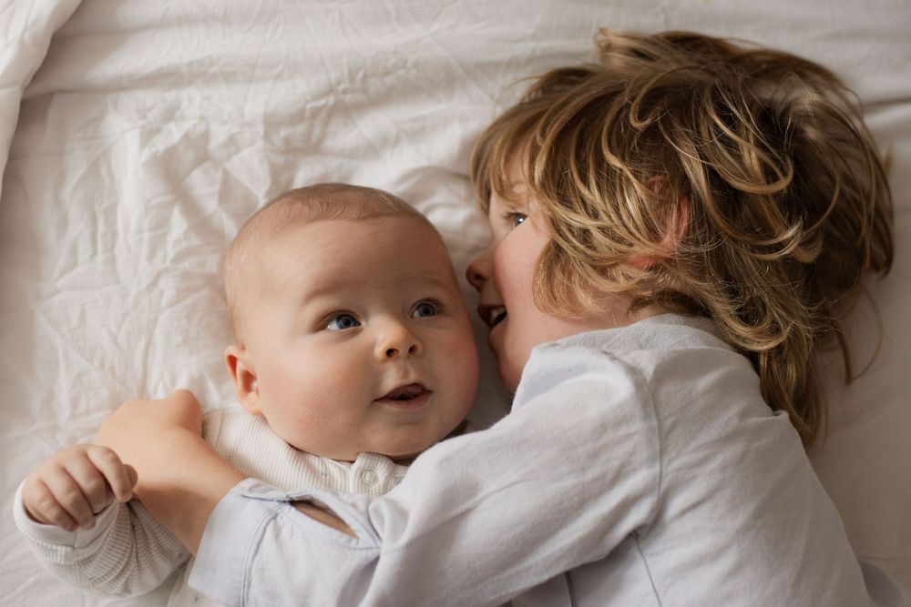 Gentle embrace captured in soft white tones on bedding.