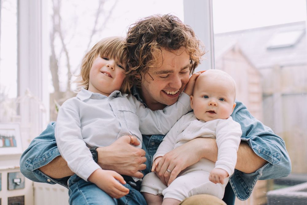Candid family moment with denim and white clothing by window light.