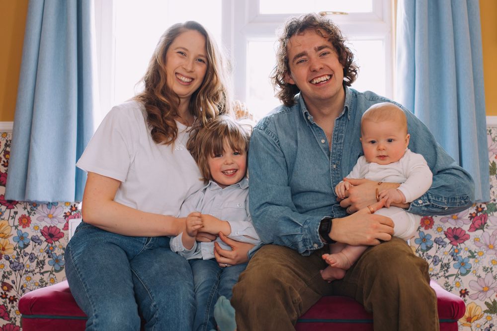 Happy family laughing together while relaxing on a couch in a sunny living room.