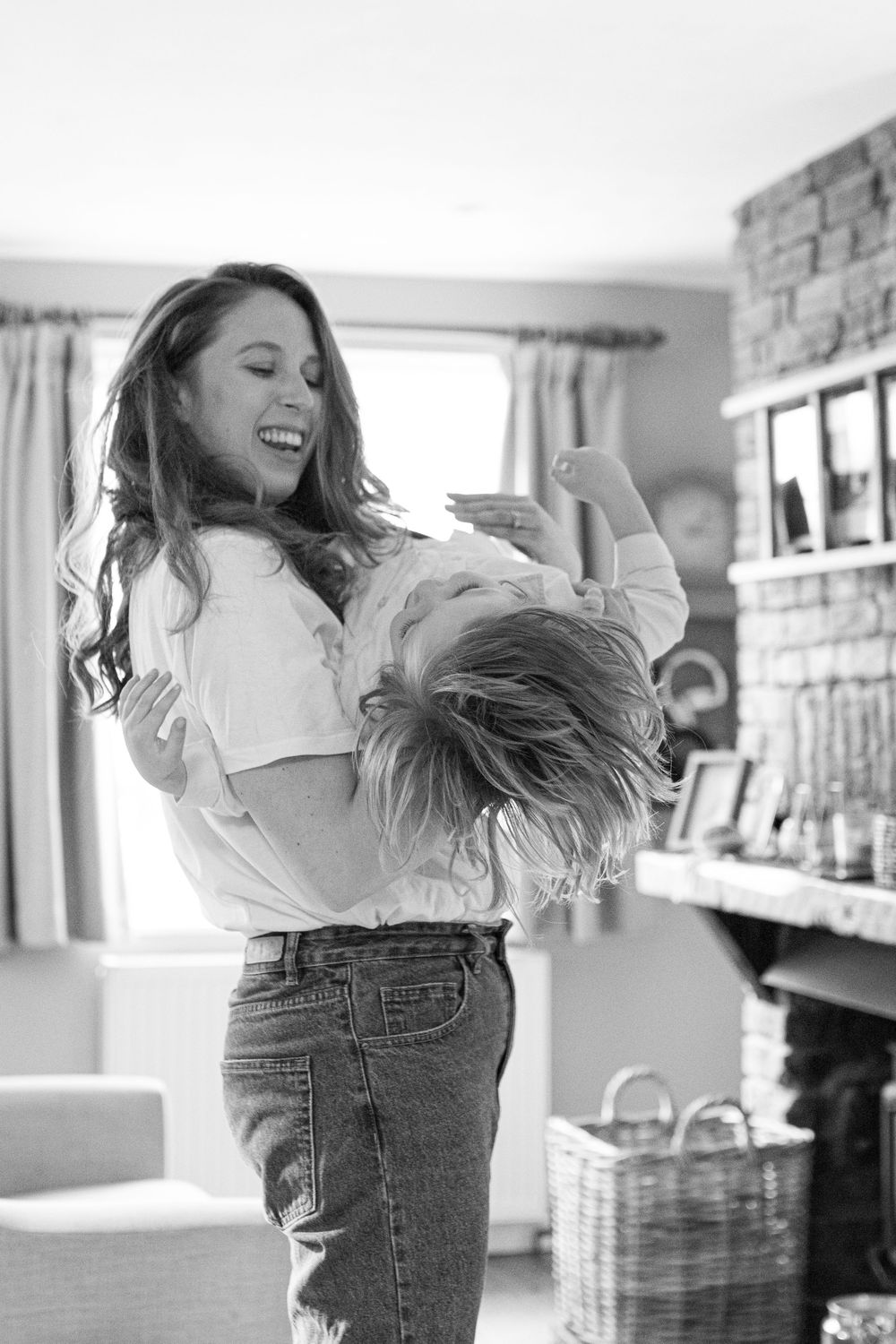 Woman in jeans and white shirt dancing joyfully in a bright indoor space.