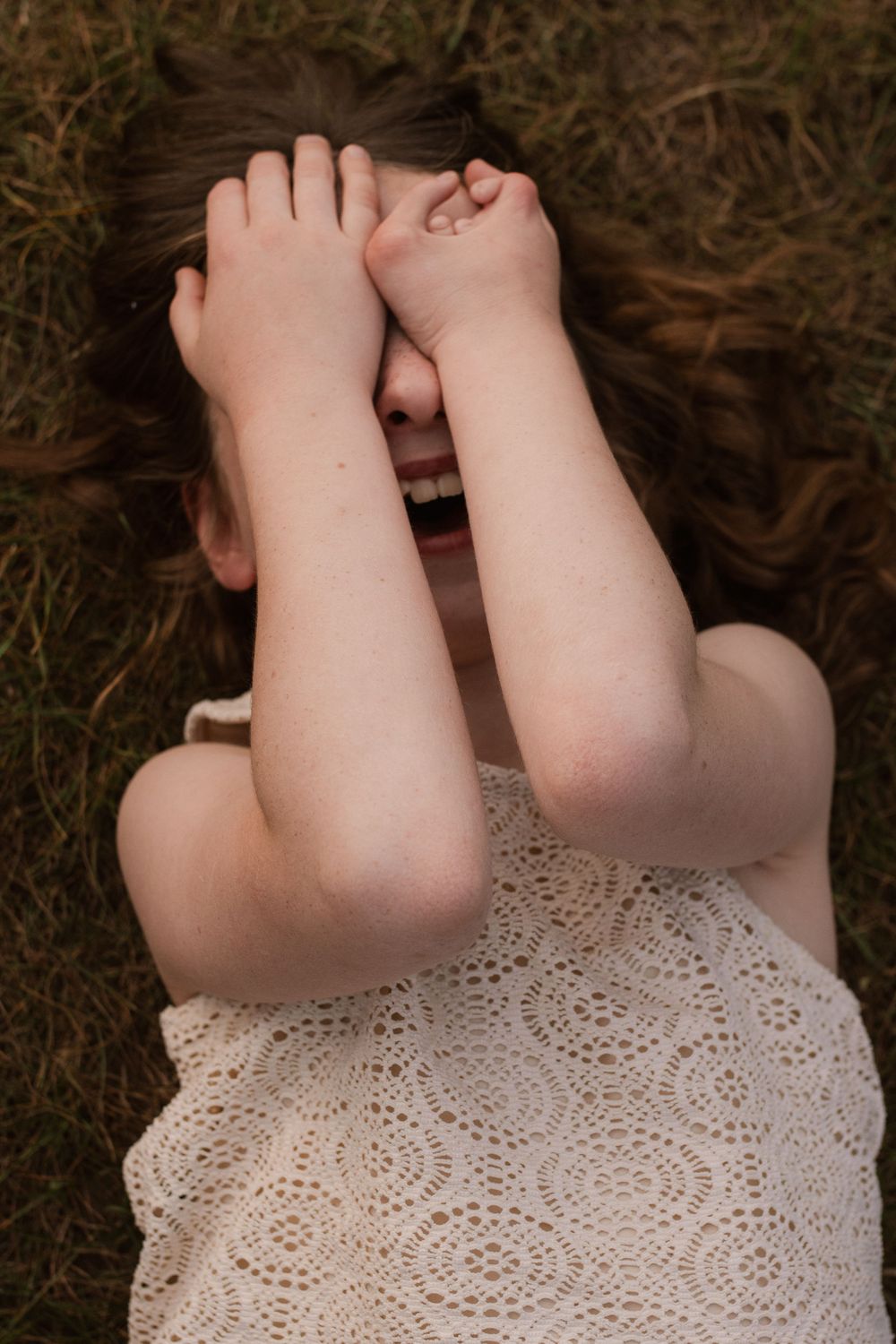Close-up view of lace dress detail against dark grass background.