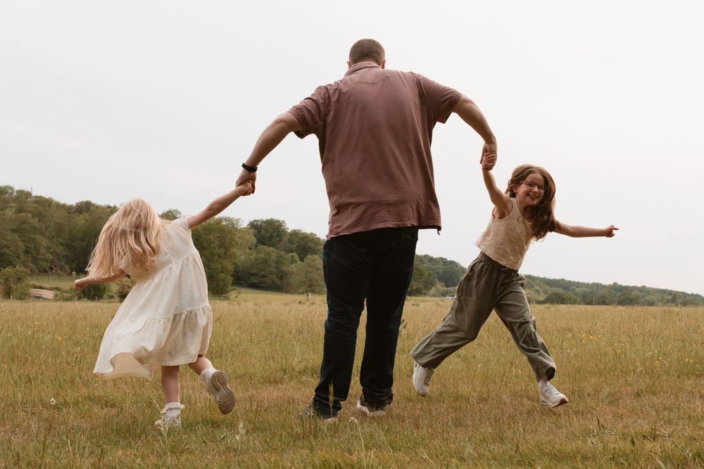 Playful figures run and jump through a sunlit meadow in a series of connected motion shots.