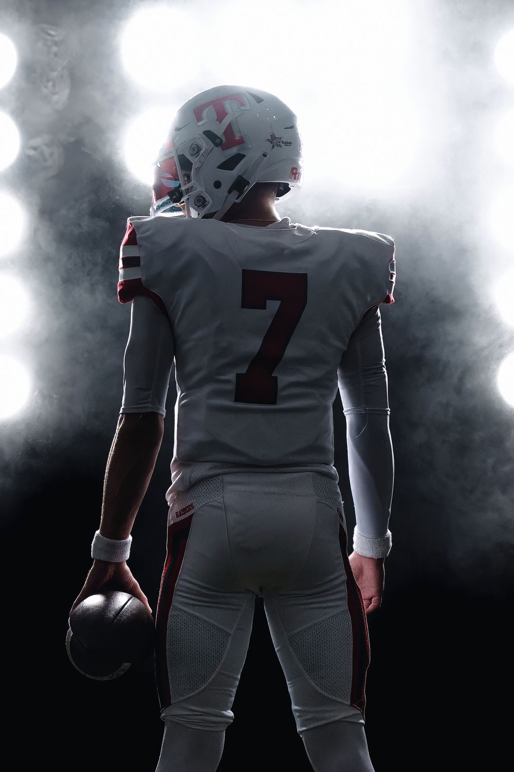 Dramatic silhouette of football player wearing number 7 jersey in white uniform, standing in atmospheric smoke effect.