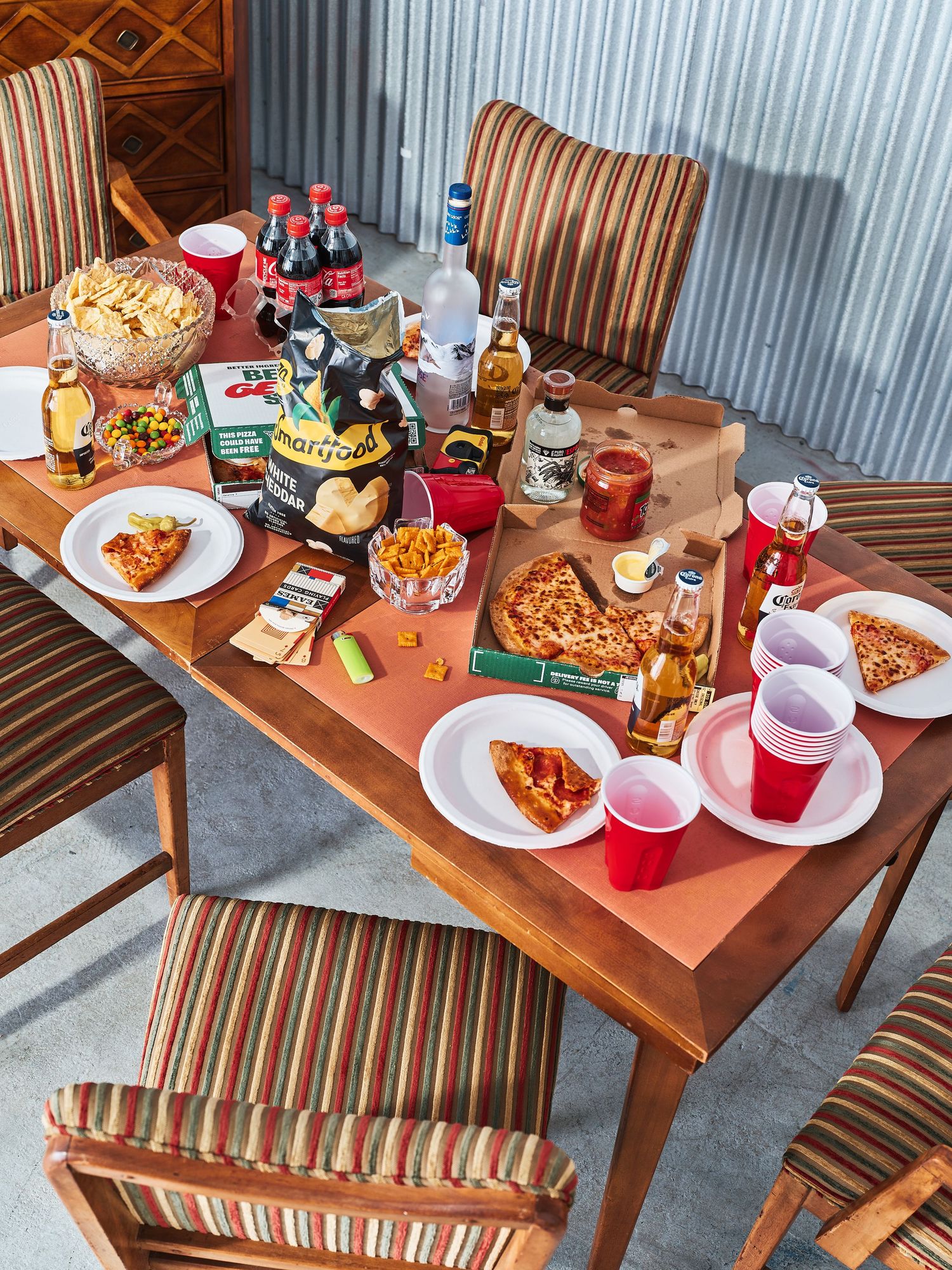 Overhead view of table spread with pizza, snacks, and red cups for casual gathering.
