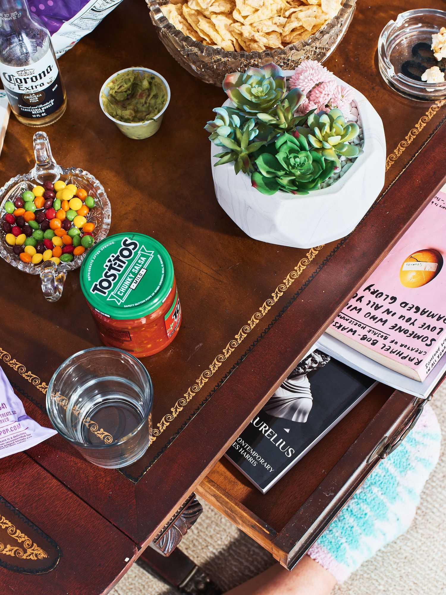 Party snack spread featuring chips, candy, and succulent centerpiece on wooden table.