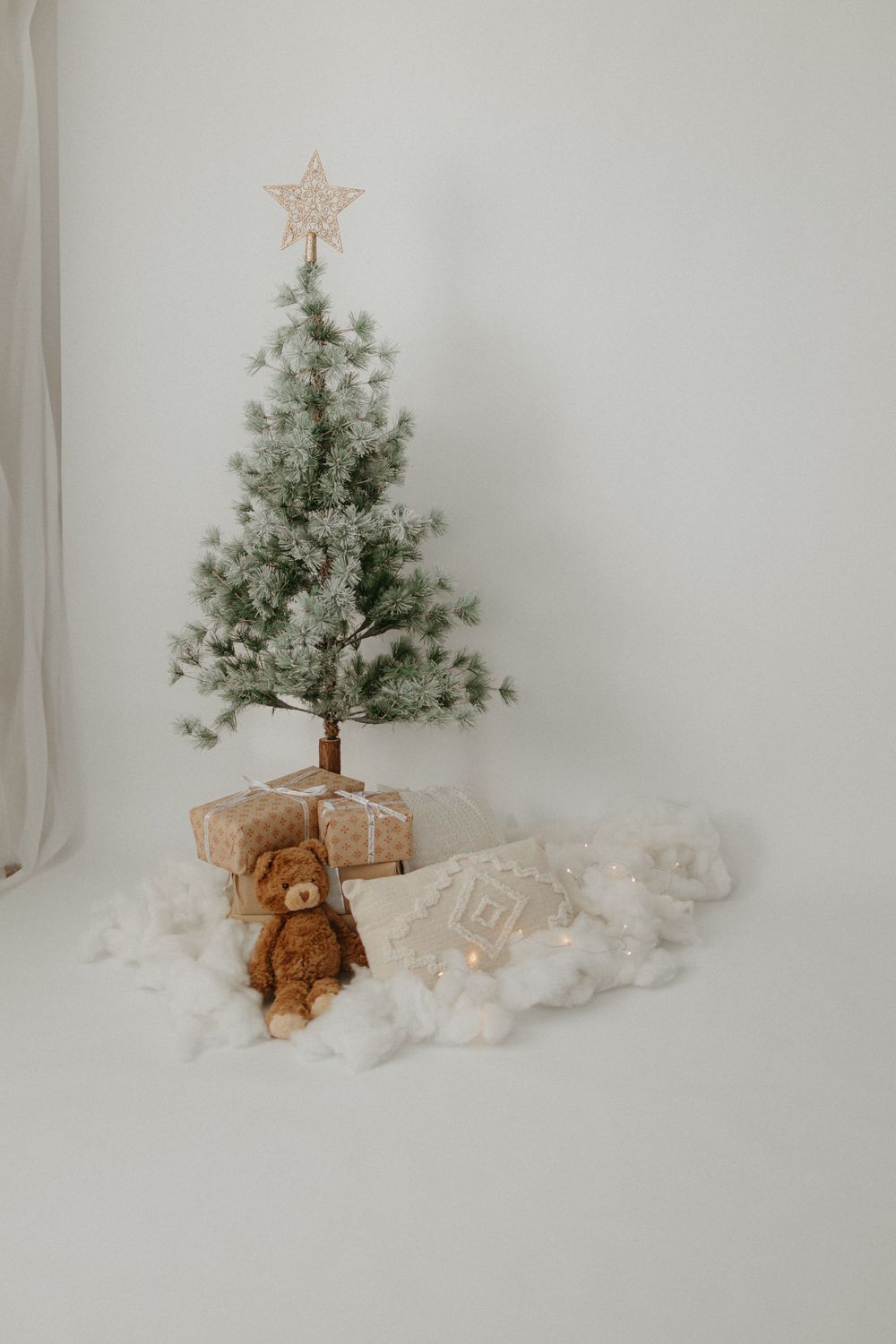 Minimalist Christmas tree with gold star topper and teddy bear display.