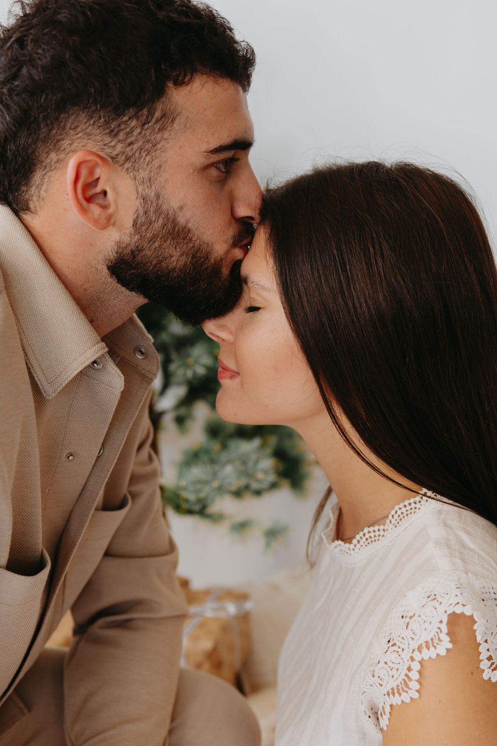 An intimate close-up of a couple sharing a tender moment against a light background.