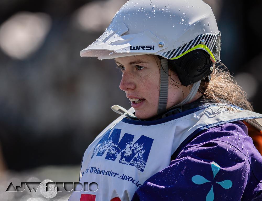 Competitive kayaker wearing white helmet and purple jacket during winter sporting event.