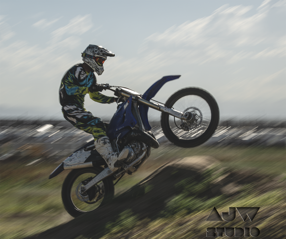Motocross rider performing jump on dirt bike against cloudy sky.