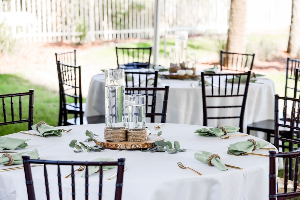 Elegant wedding reception table settings with black chiavari chairs and white linens.