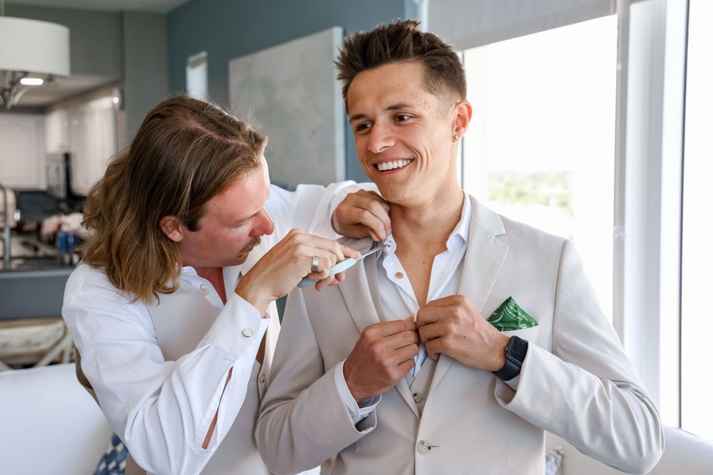 Candid pre-wedding moment of two people in white suits.