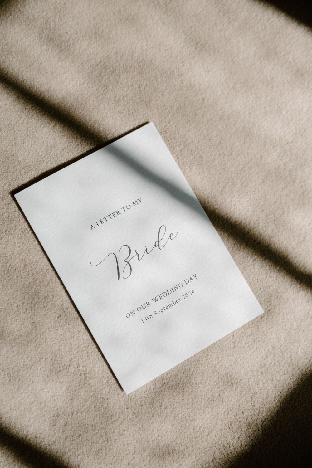 Wedding invitation with 'Bride' text in calligraphy on white paper with dramatic shadows.