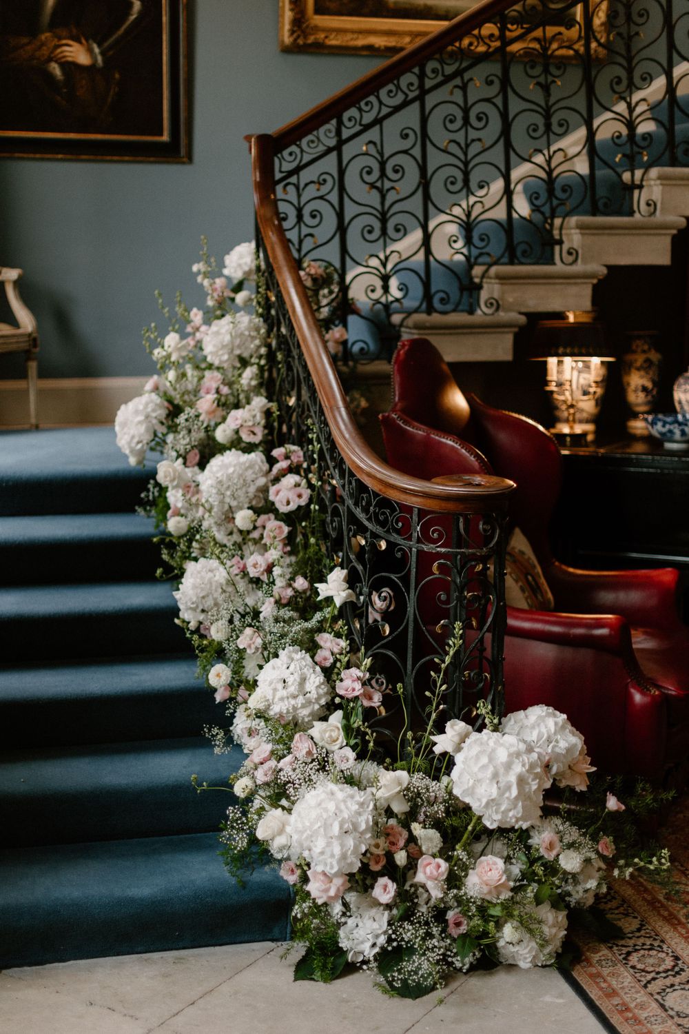 Elegant staircase adorned with cascading white floral arrangements and ornate iron railings.