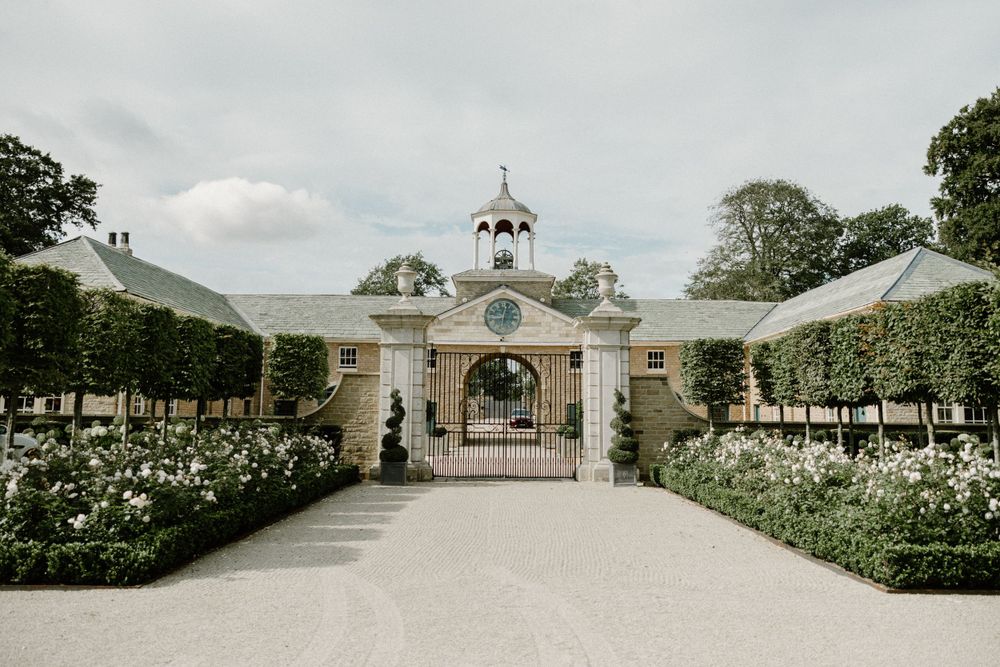 Symmetrical entrance gates with manicured gardens and classical architecture.