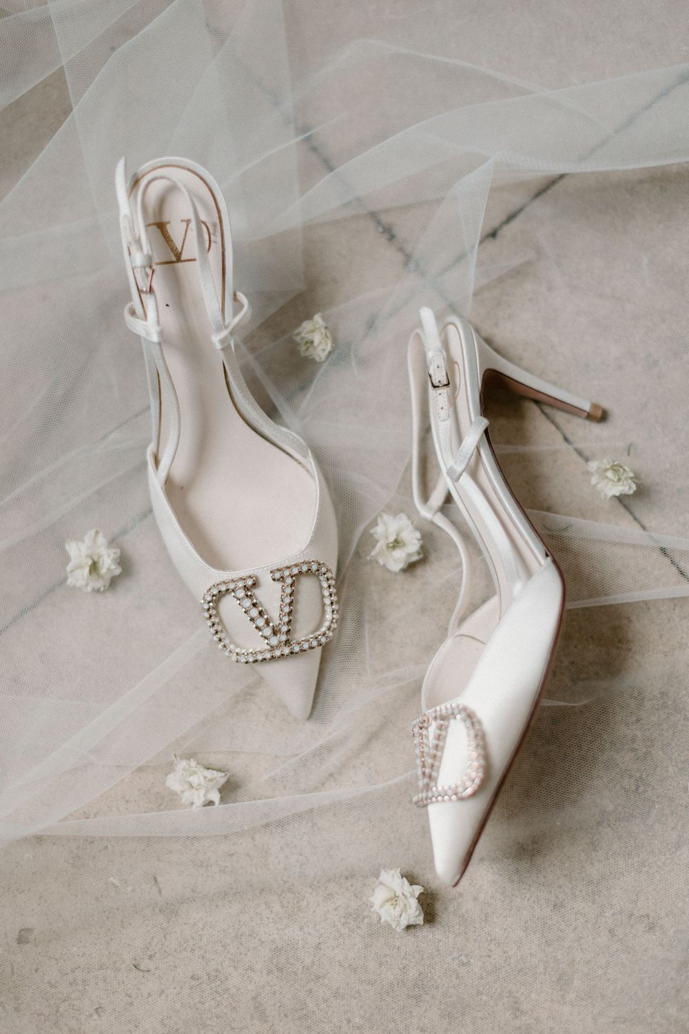 Elegant white bridal shoes with crystal embellishments on tulle fabric.