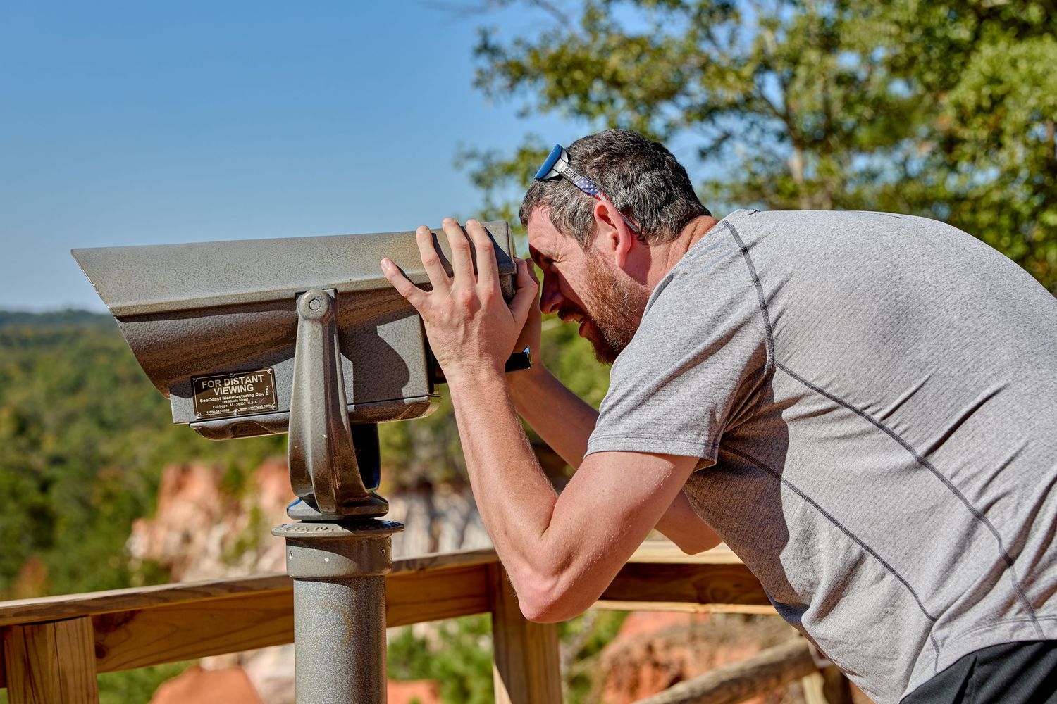 Visitor looking through coin-operated viewfinder at scenic overlook.