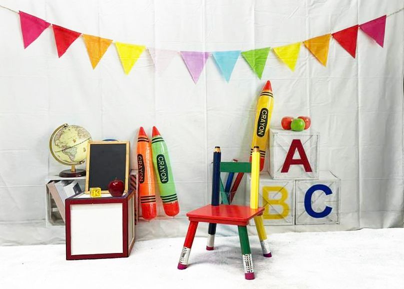 Colorful school-themed photo backdrop with ABC blocks, crayons, and rainbow bunting.