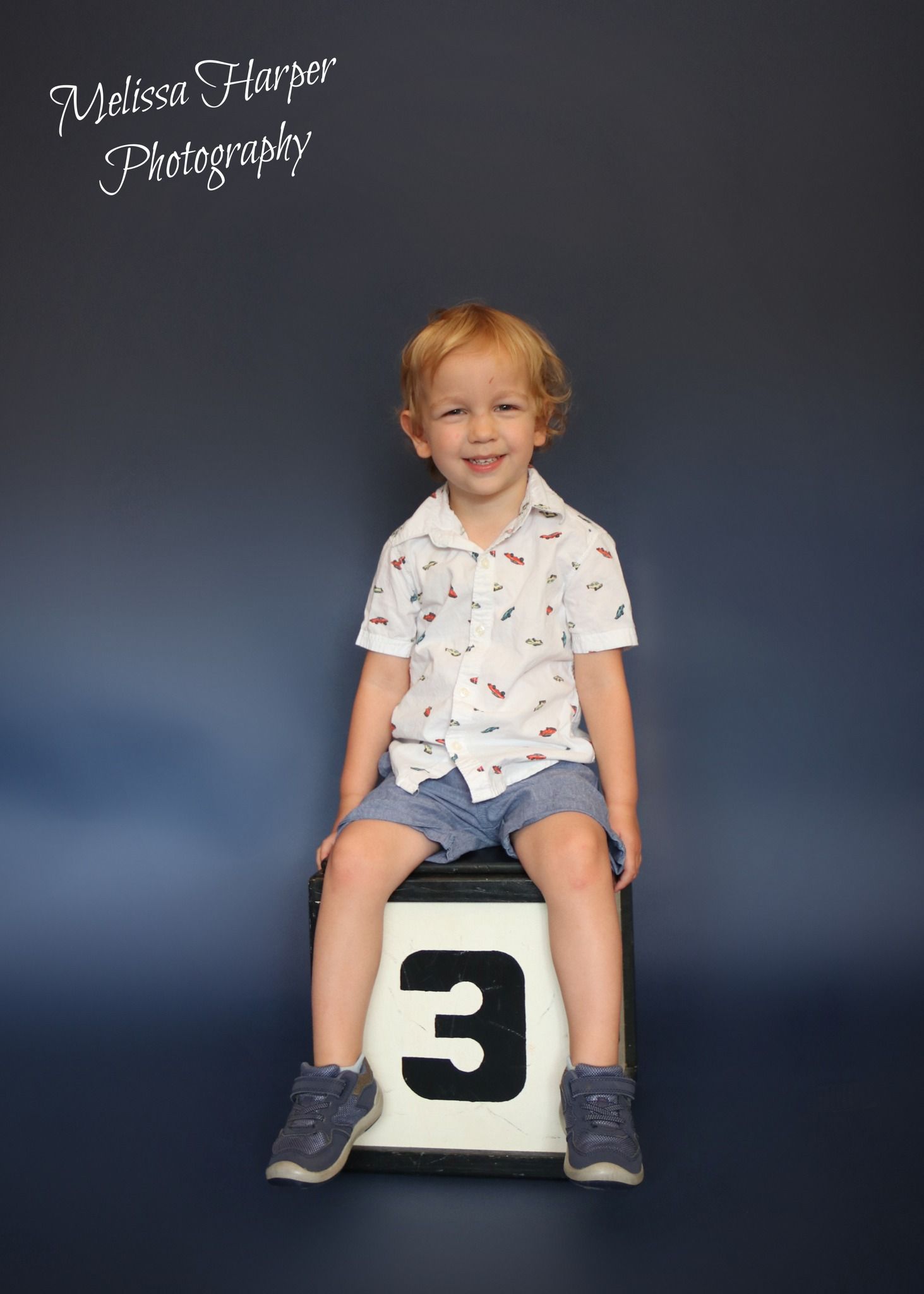 Studio photography setup with number 3 prop against blue gradient background.