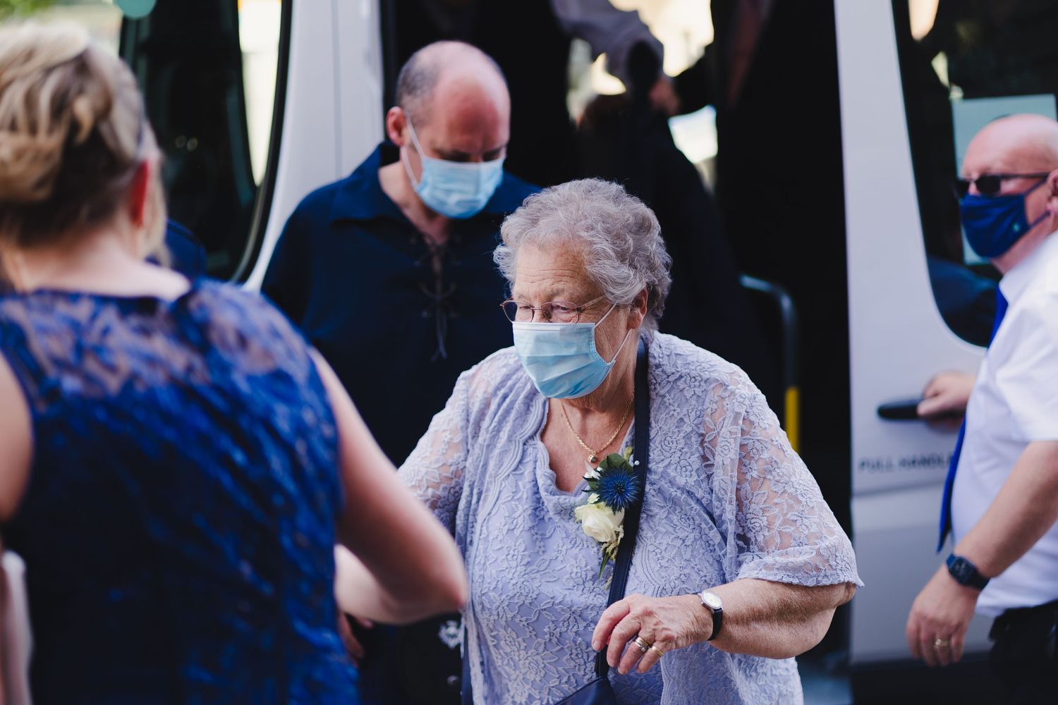 Elderly guests in protective masks gather at an outdoor event.