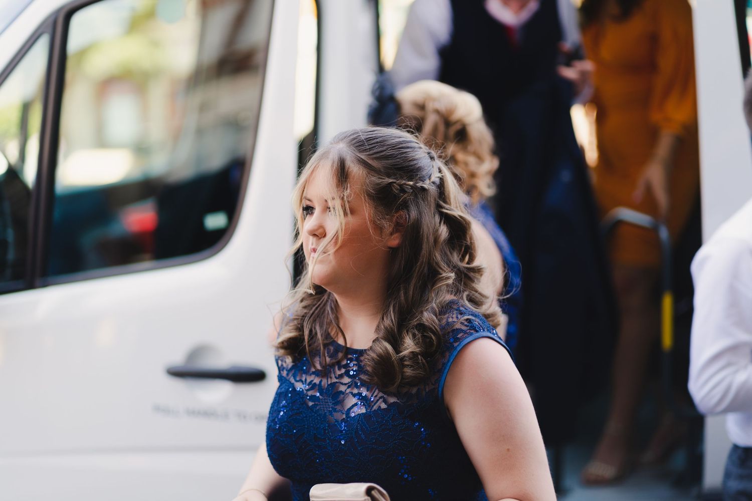 A person in a navy blue dress stands near a white van at an outdoor event.