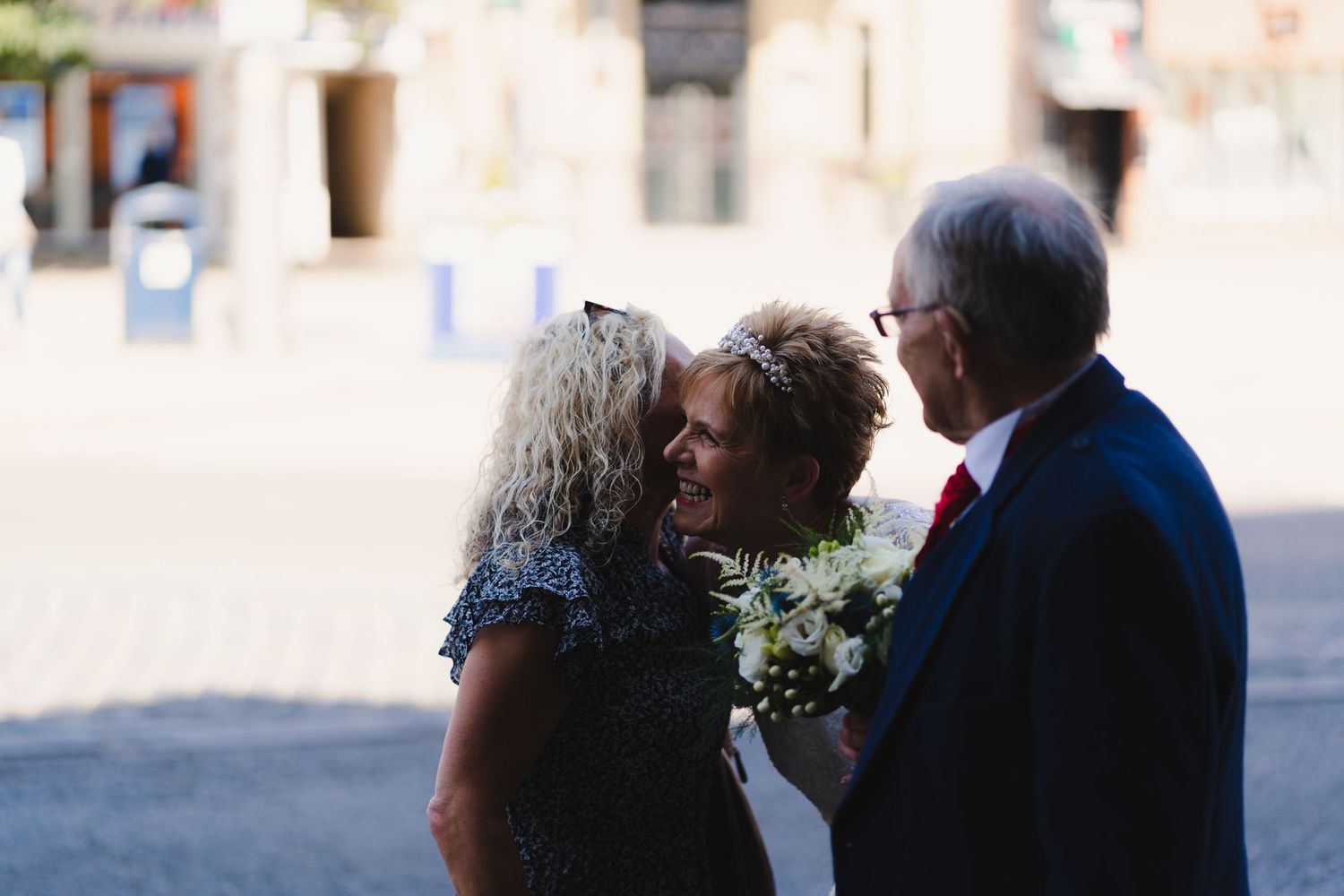 Two people share an intimate moment outdoors near a building.
