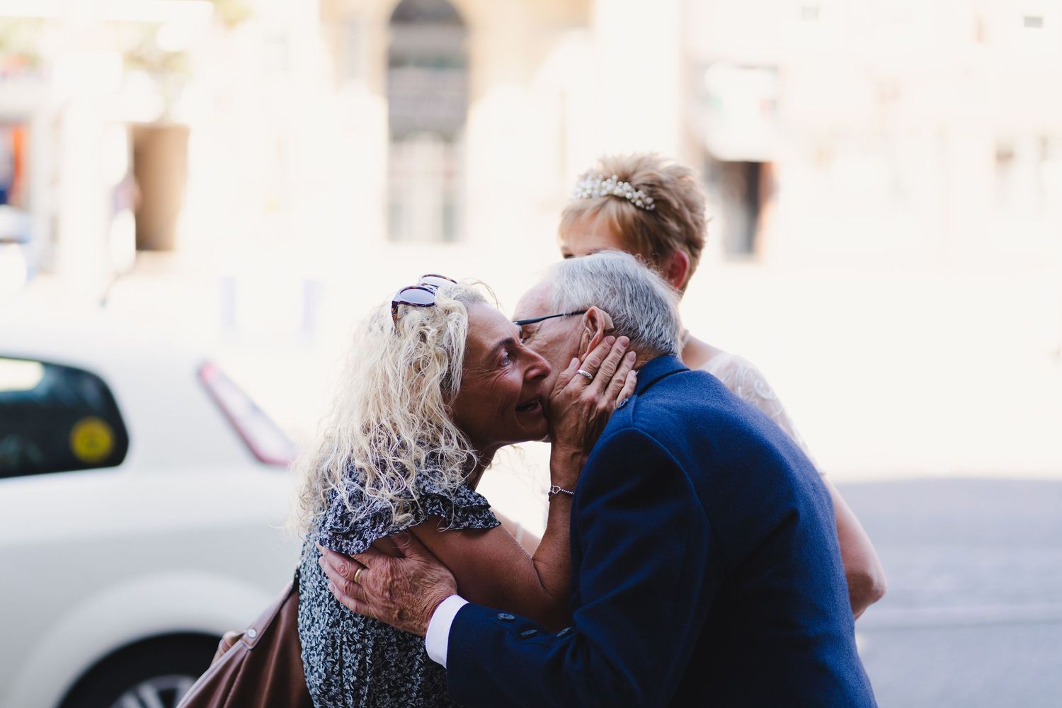 A tender moment shared between two people on a sunny street.