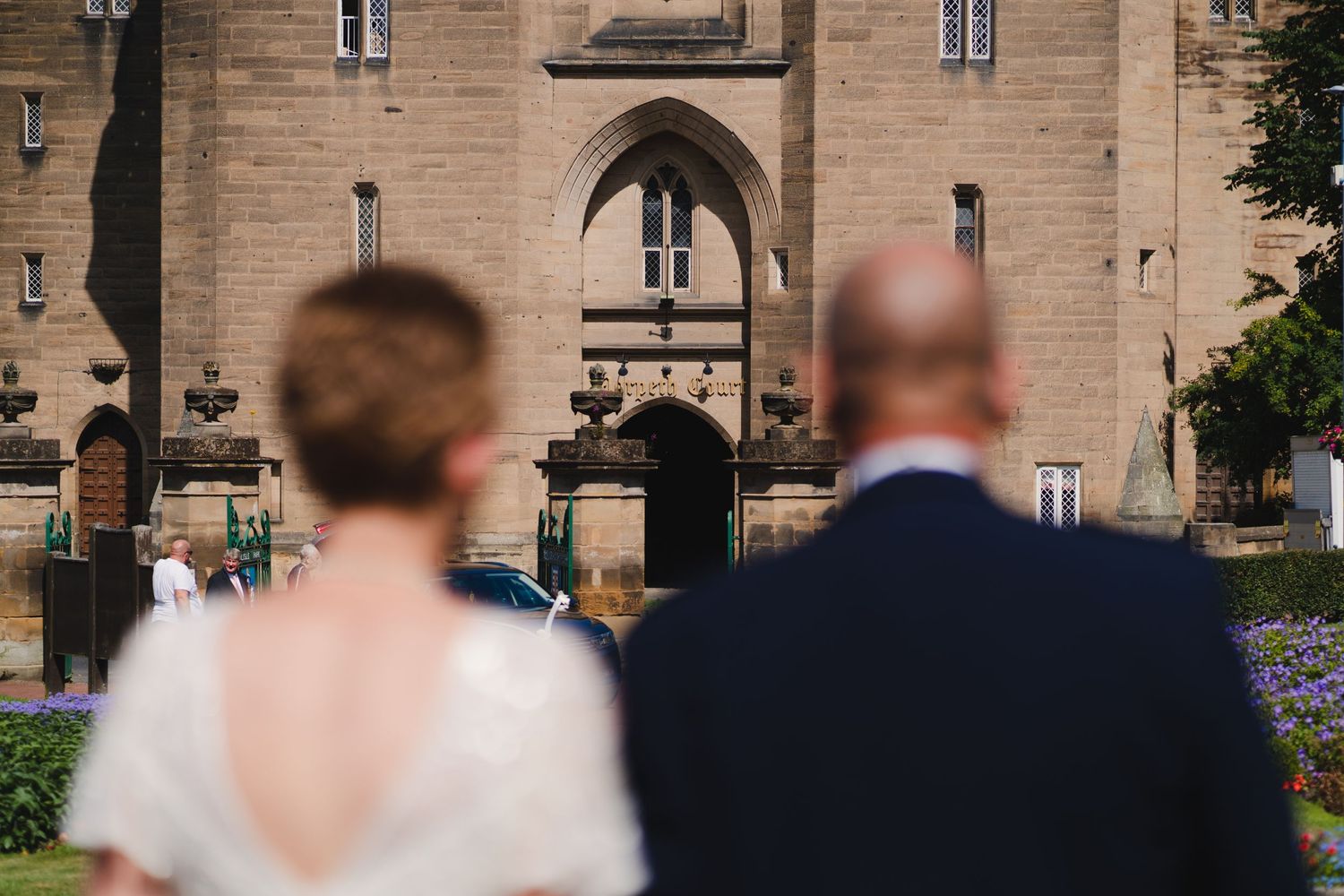 View of historic castle entrance with couple in wedding attire.