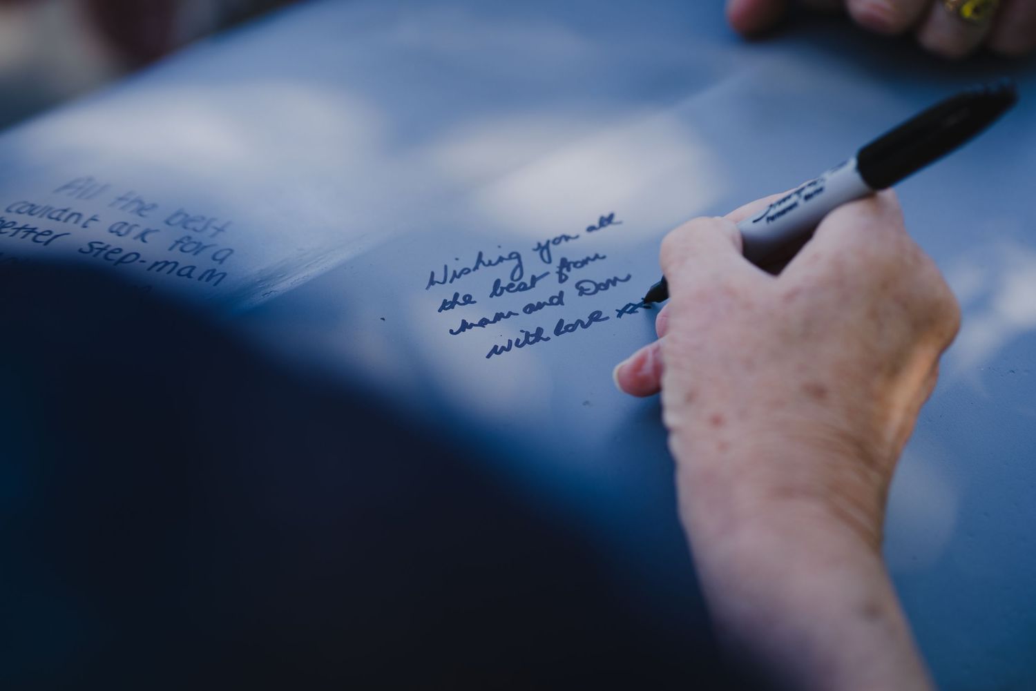 Close-up shot of someone signing a document with a pen on a blue background.