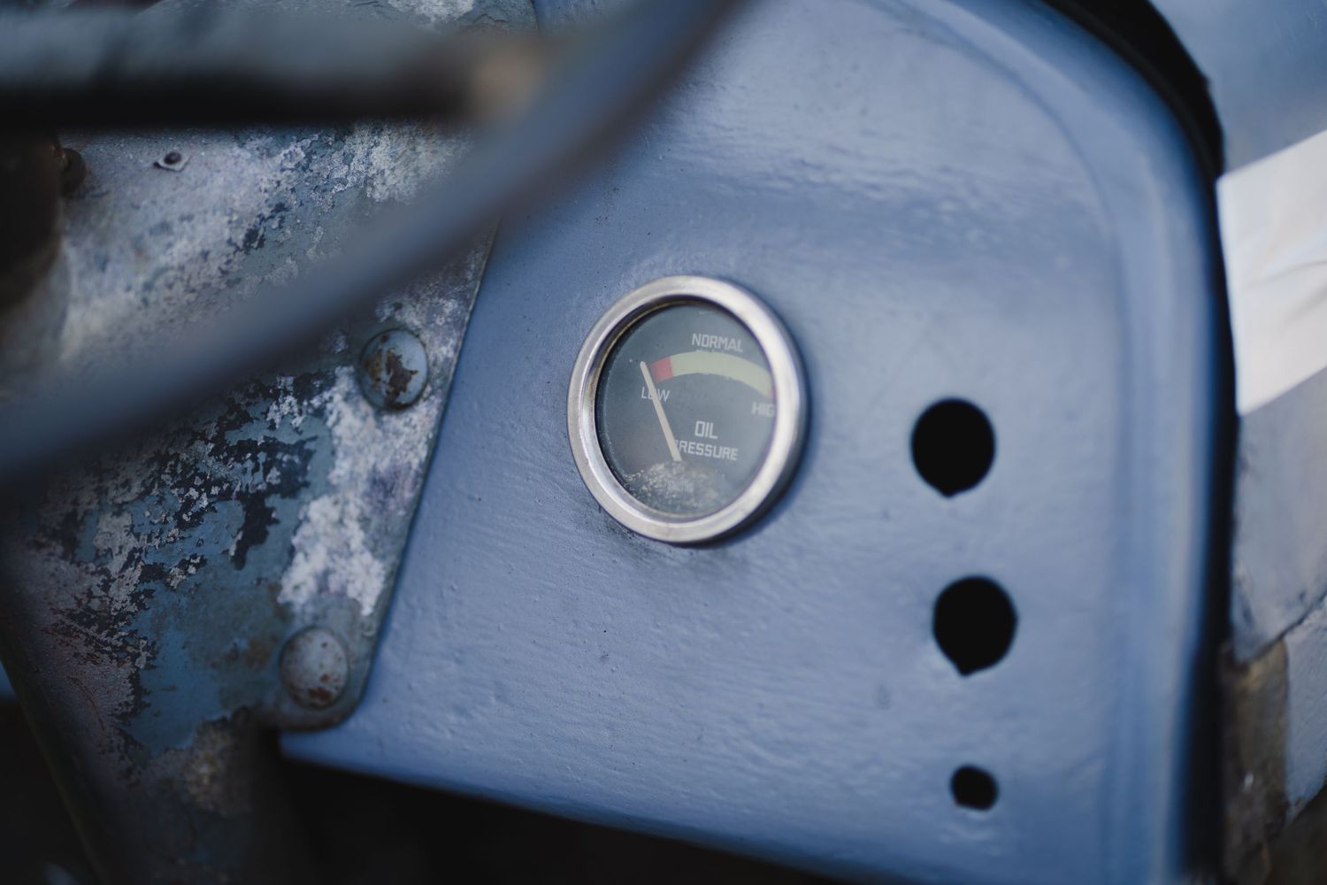 Close-up of a vintage light or gauge fixture on blue metal surface.