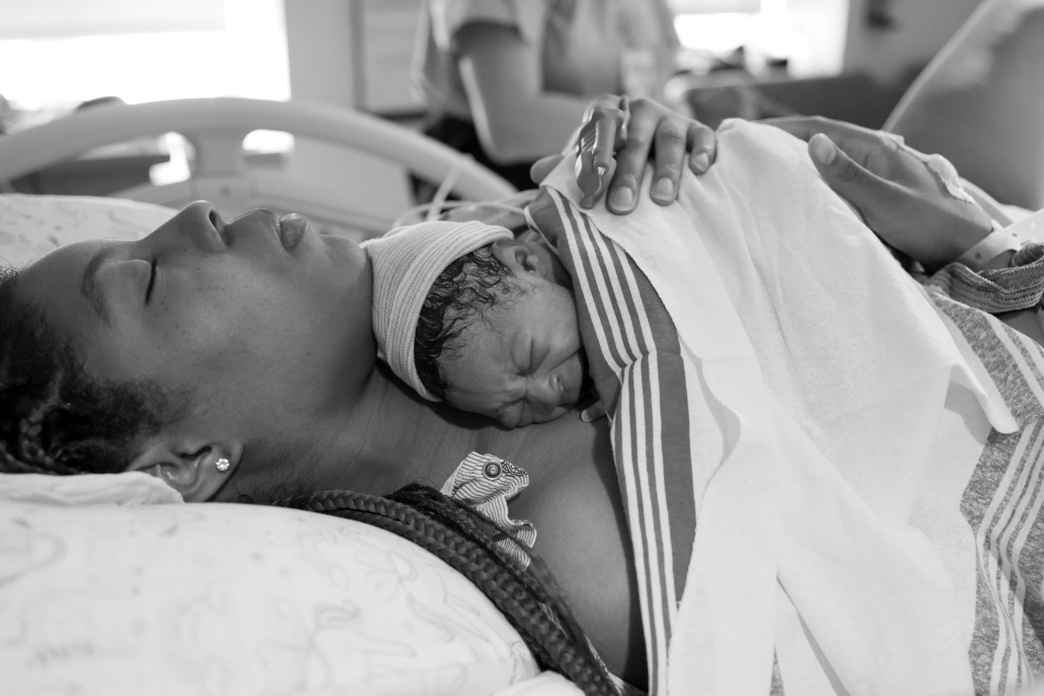 Woman holds crying newborn in hospital bed