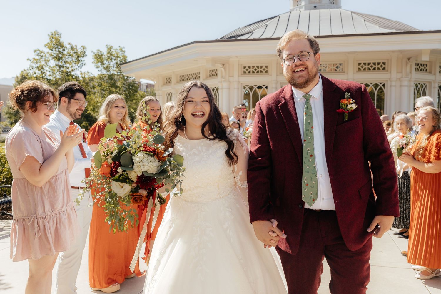 Bride and groom walking down aisle after wedding ceremony with guests cheering.