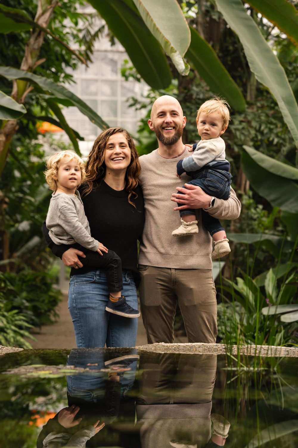 Natural light family photo under arched greenhouse ceiling with vibrant foliage – Southeast MI photography