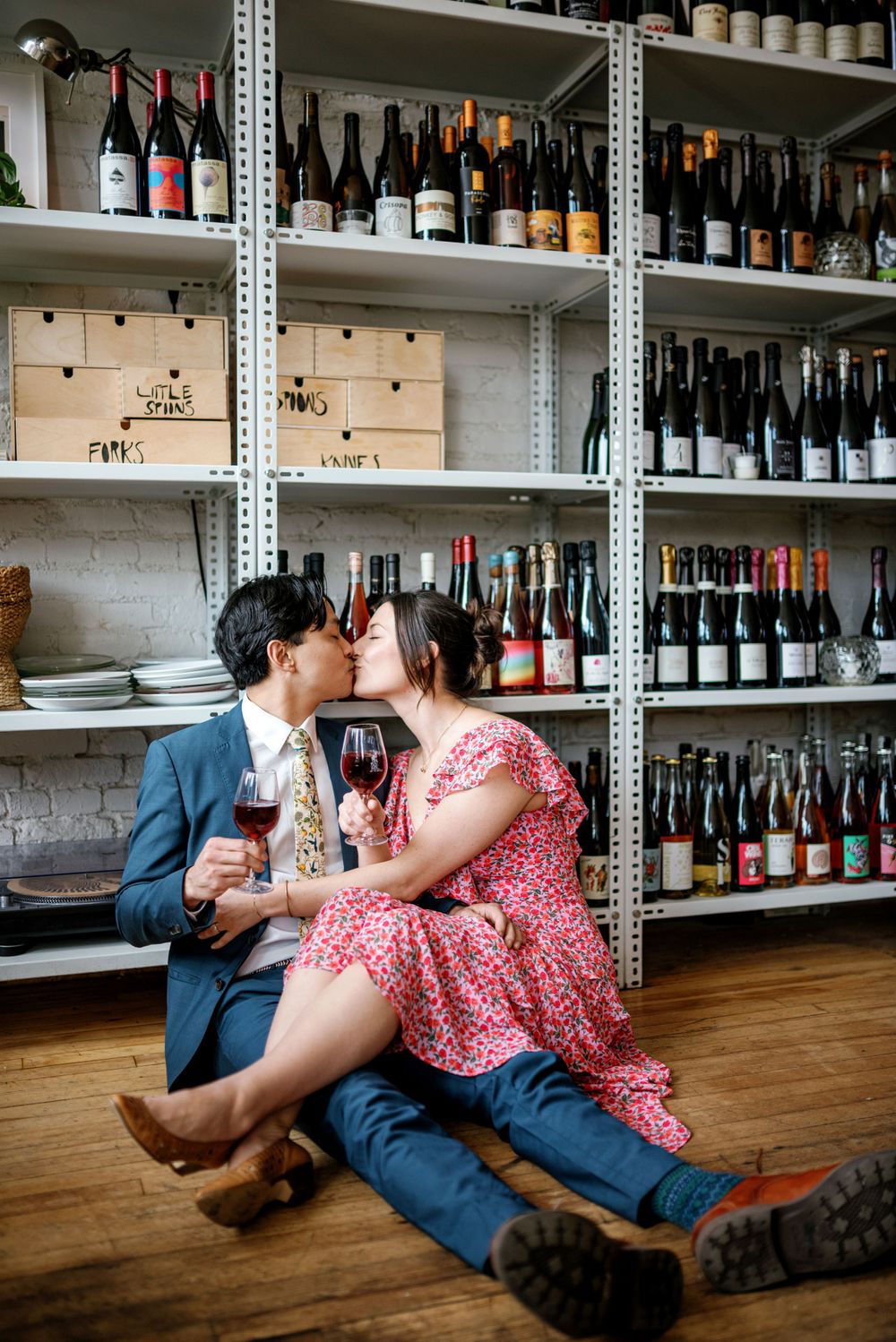 Couple sharing wine and romantic moment in front of industrial wine storage shelving in restaurant cellar.