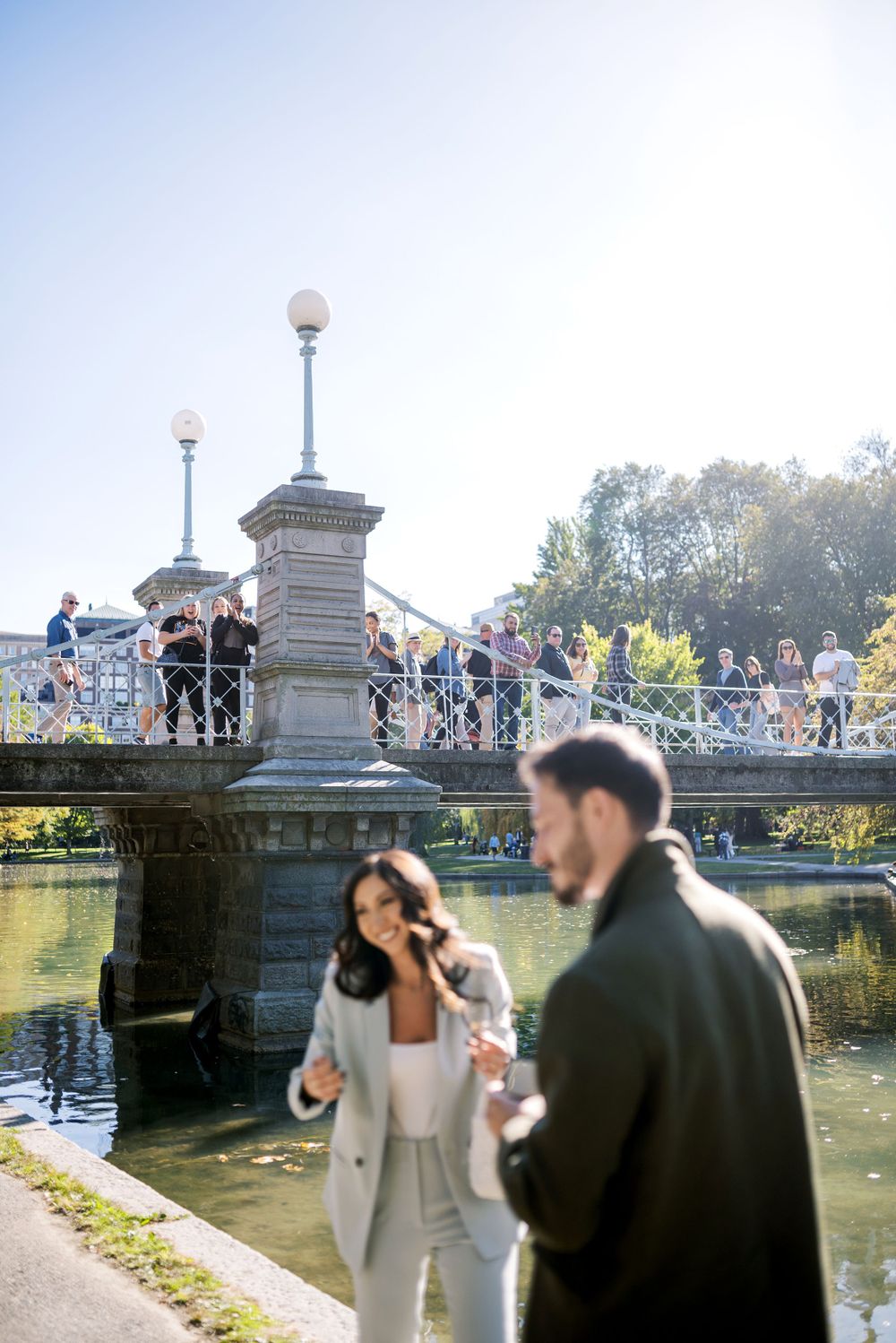 Special moment captured at historic bridge in Boston Public Garden with onlookers in background.