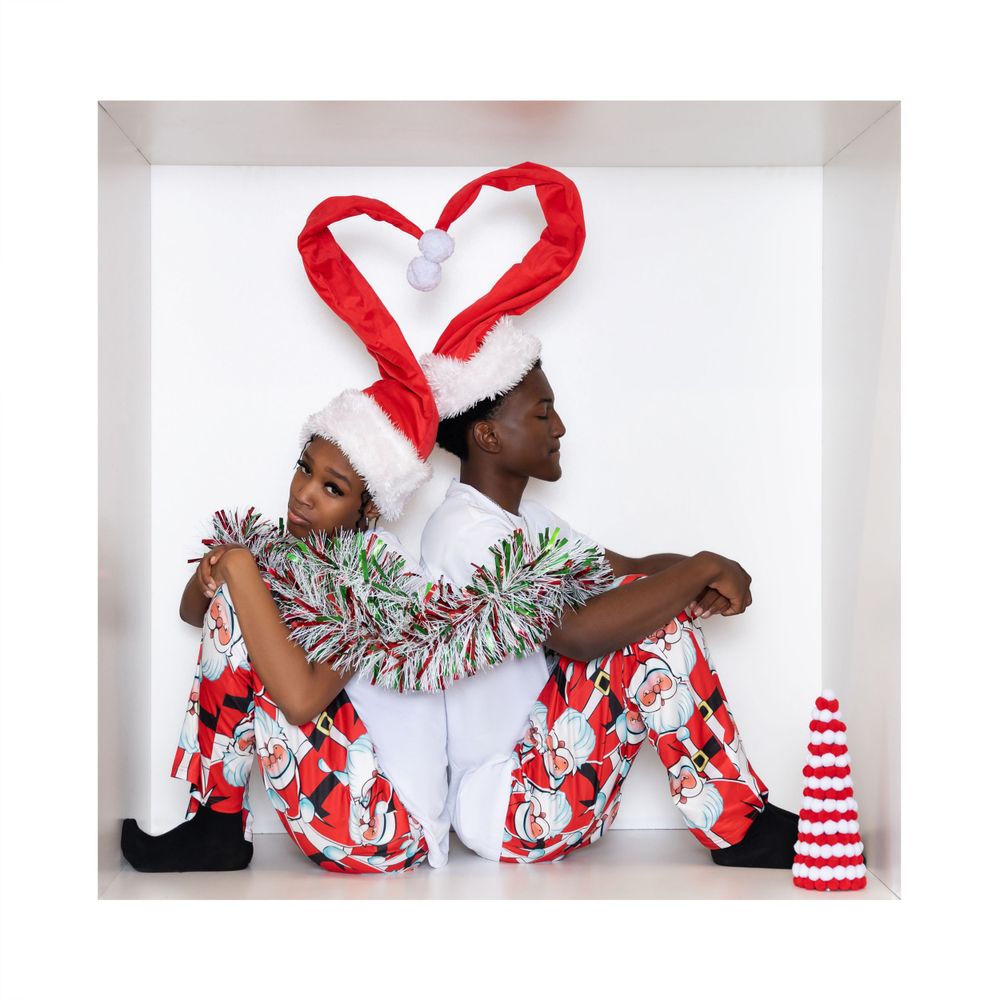 Creative Christmas portrait with Santa hats forming heart shape against white background.