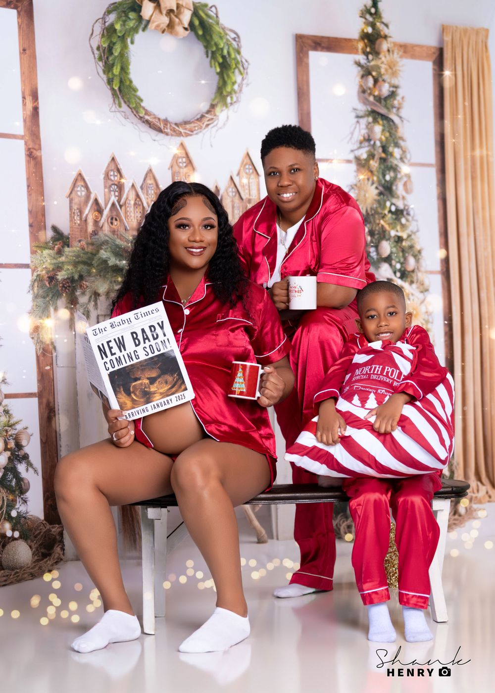 Family in matching red outfits poses for Christmas photo with pregnancy announcement book.
